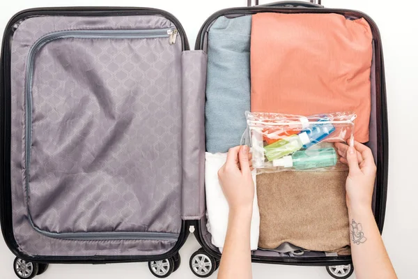 Vista ritagliata della donna imballaggio borsa da viaggio su sfondo bianco — Foto stock