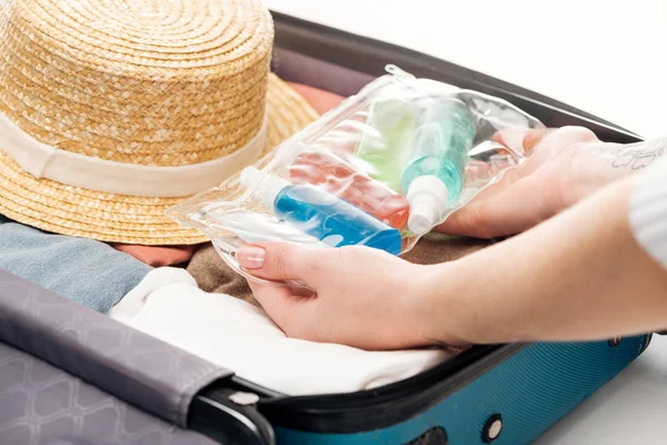 Vista ritagliata della donna imballaggio borsa da viaggio con sacchetto cosmetico con bottiglie — Foto stock