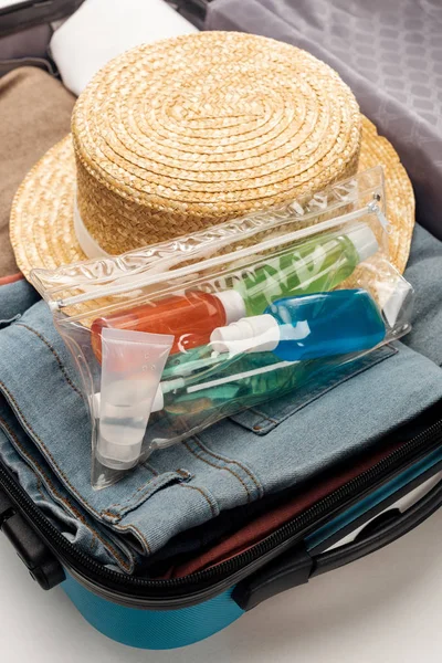 Sac de voyage avec sac cosmétique avec bouteilles, vêtements et chapeau — Photo de stock