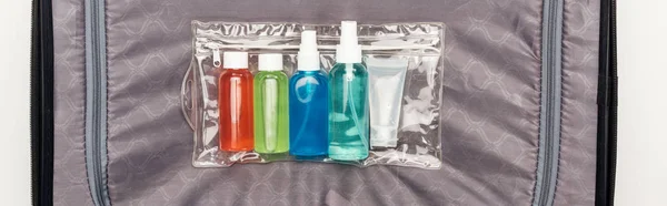 Plano panorámico de bolsa cosmética transparente con botellas de colores en la bolsa de viaje - foto de stock