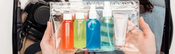 Plano panorámico de la mujer embalaje bolsa de viaje con bolsa de cosméticos con botellas de colores - foto de stock