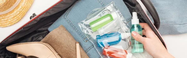 Plano panorámico de la mujer embalaje bolsa de viaje con bolsa de cosméticos con botellas de colores - foto de stock