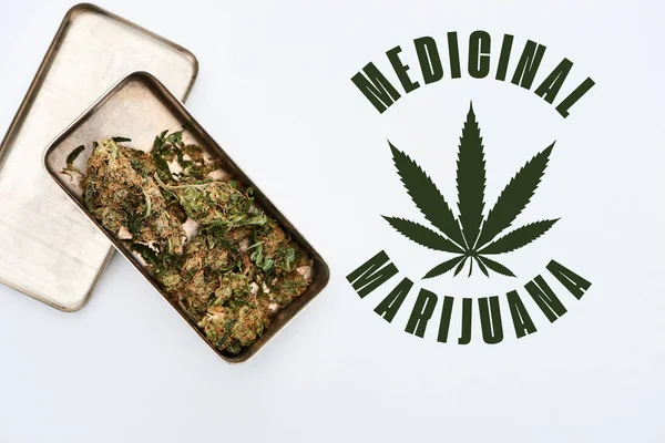 Vue du dessus des bourgeons de marijuana dans une boîte en métal sur fond blanc avec illustration de marijuana médicale — Photo de stock
