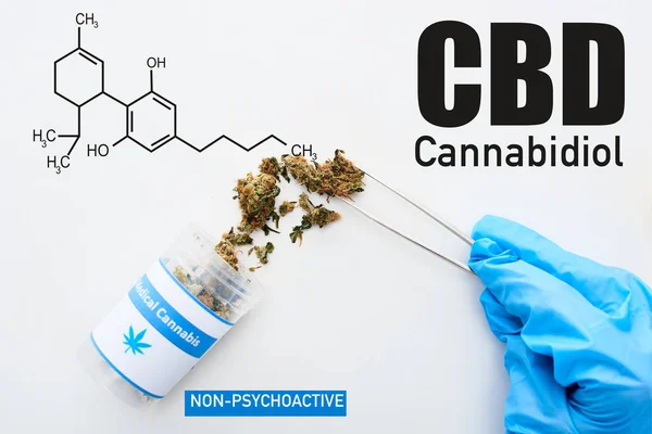 Обрезанный вид врача в синей перчатке, держащего медицинскую марихуану с пинцетом на белом фоне с иллюстрацией молекул CBD — стоковое фото