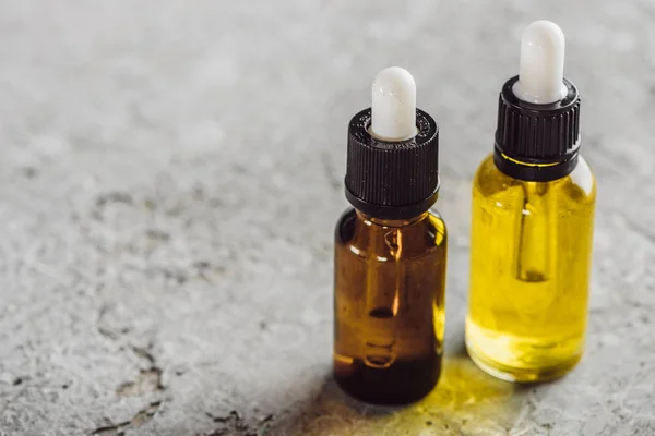 Close up view of bottles with natural serum on grey stone surface — Stock Photo