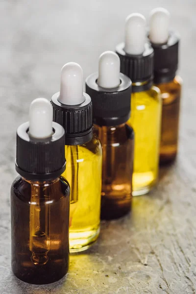 Close up view of bottles with natural serum on grey stone surface — Stock Photo