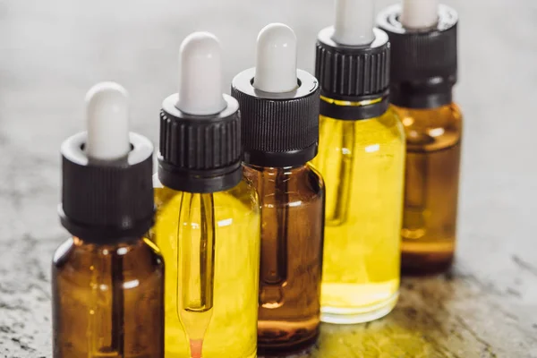 Close up view of bottles with natural serum on grey stone surface — Stock Photo