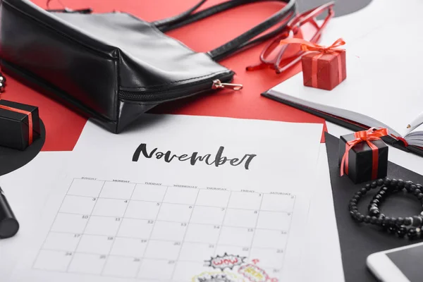 Foco seletivo do calendário com letras novembro, saco, presentes e óculos de sol — Fotografia de Stock