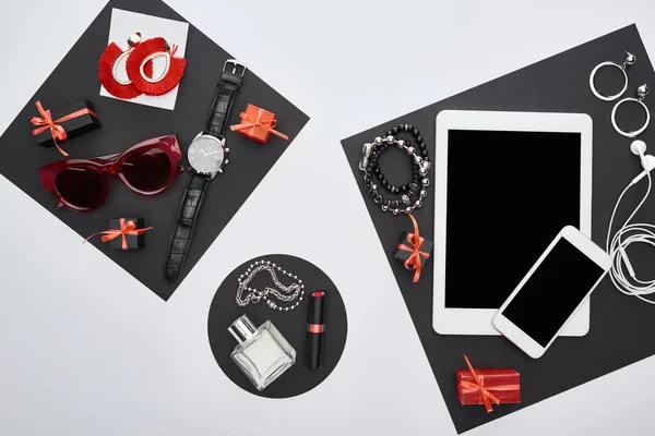 Vista superior de gadgets, cajas de regalo, gafas de sol, perfume, reloj de pulsera, pendientes, auriculares, pulseras, lápiz labial - foto de stock