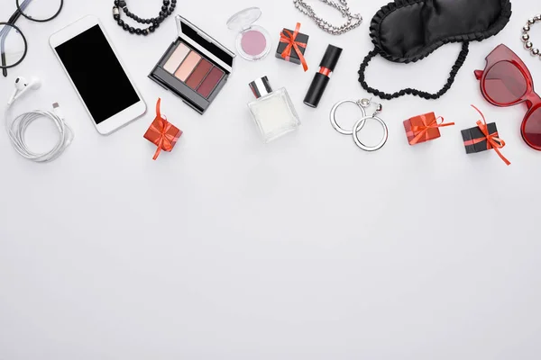Top view of gadget, gift boxes, sleeping mask, sunglasses, perfume, earrings, earphones, bracelets, decorative cosmetics — Stock Photo