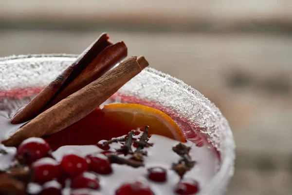 Vista ravvicinata del vin brulè speziato rosso con bacche, anice, fette di arancia e cannella in vetro decorato con zucchero — Foto stock