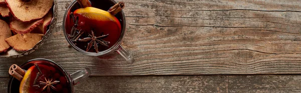 Panoramic shot of red spiced mulled wine with berries, anise, orange slices and cinnamon on wooden rustic table — Stock Photo