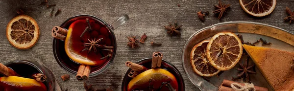 Top view of red spiced mulled wine with berries, anise, orange slices and cinnamon on wooden table, panorama shot — Stock Photo