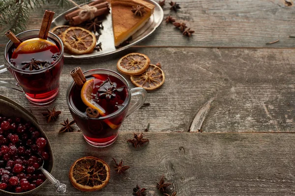 Vin brulè speziato rosso vicino a bacche, anice, fette di arancia e cannella su tavolo rustico in legno con spazio copia — Foto stock