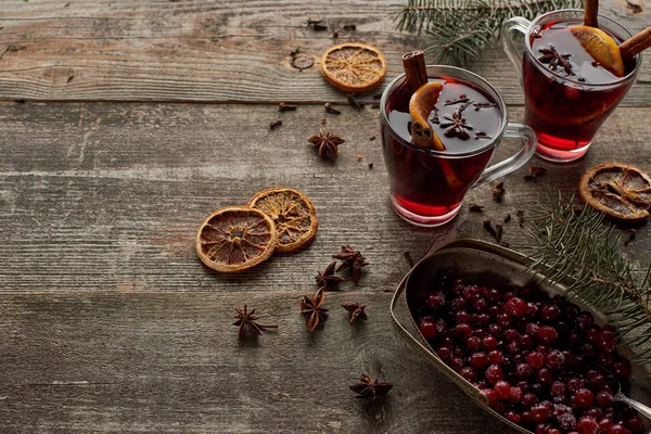 Red spiced mulled wine with fir branch, berries, anise, orange slices and cinnamon on wooden rustic table — Stock Photo