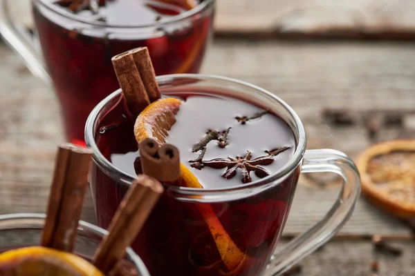 Close up view of red spiced mulled wine with berries, anise, orange slice and cinnamon on wooden rustic table — Stock Photo