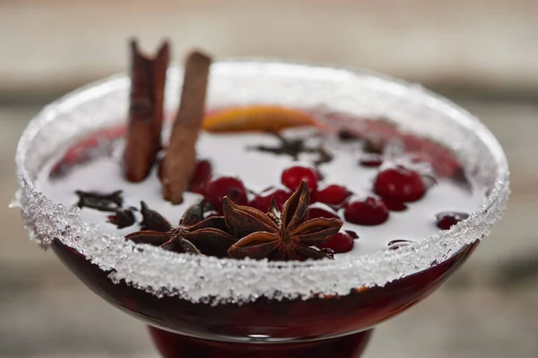 Close up view of red spiced mulled wine with berries, anise, orange slice and cinnamon in glass with sugar — Stock Photo