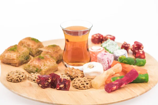 Wooden board with delicious turkish sweets and tea isolated on white — Stock Photo