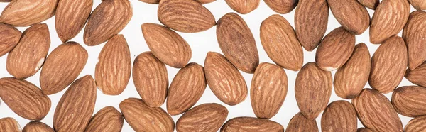 Top view of almond nuts scattered isolated on white, panoramic shot — Stock Photo