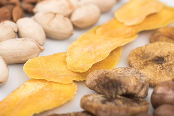 Vista de cerca de pistachos, mango seco e higos aislados en blanco - foto de stock