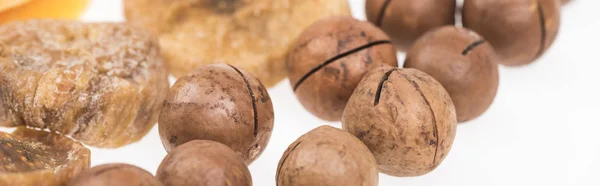 Vue rapprochée de tranches de mangue séchées, de figues et de noix de macadamia isolées sur plan panoramique blanc — Photo de stock