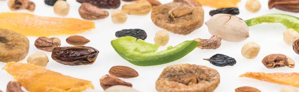 Vista de cerca de sabrosos frutos secos surtidos, frutas secas y frutas confitadas aisladas en blanco, plano panorámico - foto de stock