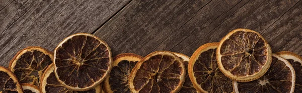 Panoramic shot of dried orange slices on wooden background — Stock Photo