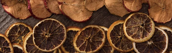 Panoramic shot of dried orange and apple slices on wooden background — Stock Photo