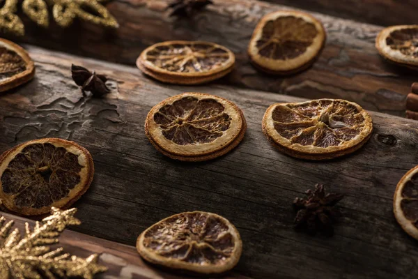 Сушені цитрусові скибочки з анісом та декоративними сніжинками на дерев'яному фоні — стокове фото