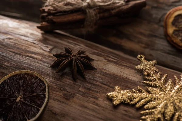 Rodajas de cítricos secos con anís, varillas de canela y copos de nieve decorativos sobre fondo de madera - foto de stock