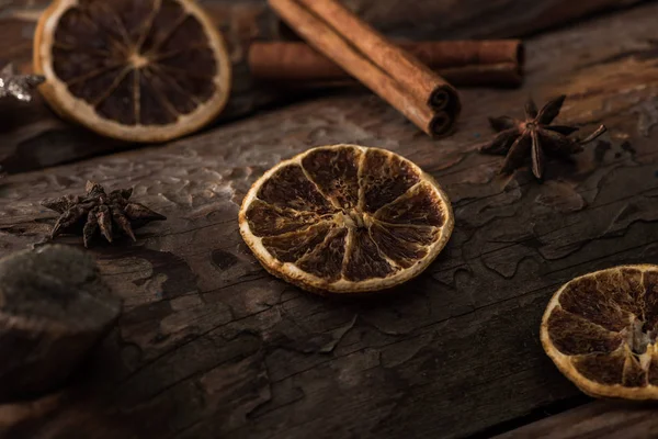 Сушеные цитрусовые ломтики с анисом, коричные палочки на деревянном фоне — стоковое фото