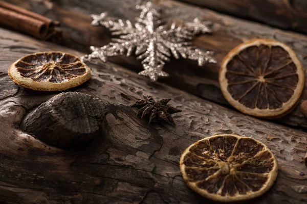 Fatias de citrinos secos com floco de neve decorativo em fundo de madeira — Fotografia de Stock