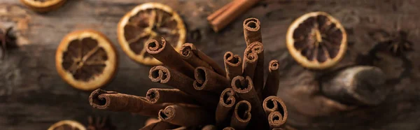 Top view of dried citrus slices with cinnamon sticks on wooden background, panoramic shot — Stock Photo