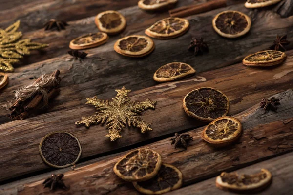 Fatias de citrinos secos com anis, paus de canela e flocos de neve decorativos no fundo de madeira — Fotografia de Stock