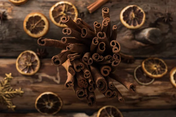 Vista superior de rodajas de cítricos secos con varillas de canela y copos de nieve decorativos sobre fondo de madera - foto de stock