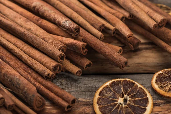 Cinnamon sticks near dried citrus slices on wooden background — Stock Photo