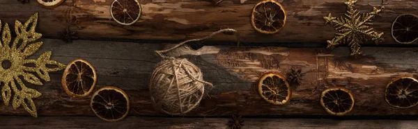 Top view of anise, dried citrus slices, ball of thread and snowflakes on wooden background, panoramic shot — Stock Photo