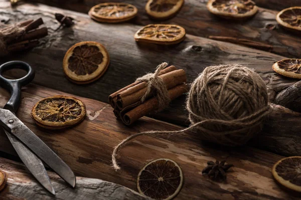 Anise, cinnamon sticks, scissors, ball of thread on wooden background — Stock Photo