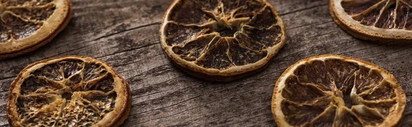 Rodajas de cítricos secos en la superficie marrón de madera, plano panorámico - foto de stock