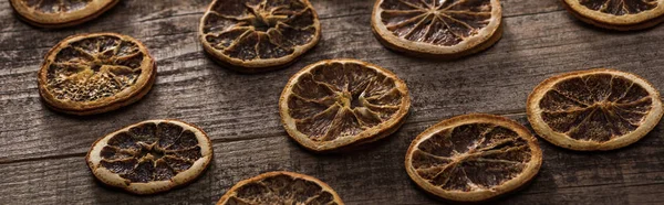 Rodajas de cítricos secos en la superficie marrón de madera, plano panorámico - foto de stock