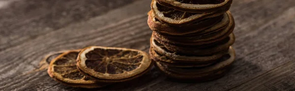 Rodajas de cítricos secos en la superficie marrón de madera, plano panorámico - foto de stock