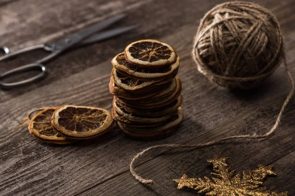 Selective focus of thread, scissors and dried citrus slices, snowflake on wooden background — Stock Photo