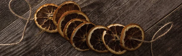 Vista superior de fatias de laranja secas na corda na superfície de madeira, tiro panorâmico — Fotografia de Stock