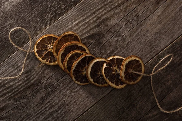 Top view of dried orange slices on rope on wooden surface — Stock Photo