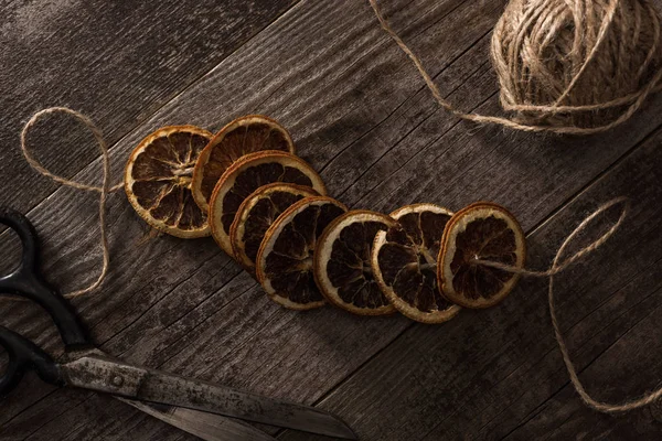 Top view of thread, scissors and dried citrus slices on wooden background — Stock Photo