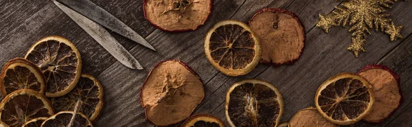 Vista superior de citrinos secos e fatias de maçã perto de floco de neve, corda e tesoura na superfície de madeira, tiro panorâmico — Fotografia de Stock