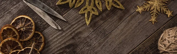 Top view of dried citrus slices near snowflakes, rope and scissors on wooden surface with copy space, panoramic shot — Stock Photo