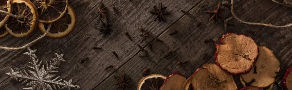 Top view of dried citrus and apple slices near snowflake and anise on wooden surface, panoramic shot — Stock Photo