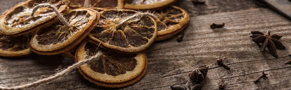 Dried citrus slices on rope near anise on wooden surface, panoramic shot — Stock Photo