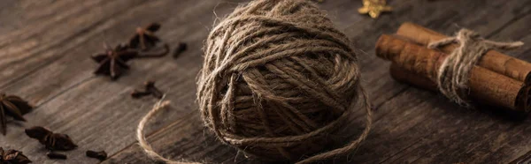 Panoramic shot of ball of thread and cinnamon on wooden surface — Stock Photo